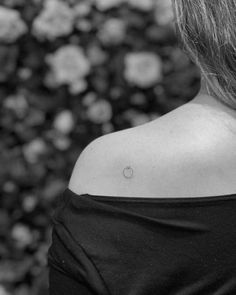 a woman with a small apple tattoo on her upper back neck and shoulder, in black and white