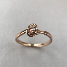 a gold ring with a diamond in the center on a white surface, close up