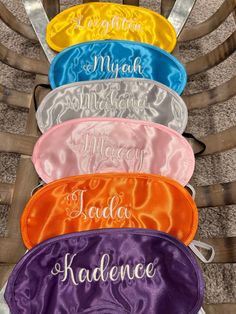 four personalized bridesmaid satin pouches in different colors and styles on a chair