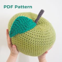 a hand holding an apple with a green leaf on it and the words knitted pattern above it