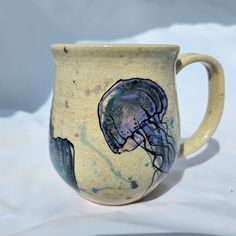 a ceramic mug with a jellyfish design on the outside and inside, sitting on a white surface