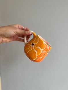 a person holding a cup in their hand with an orange flower design on the inside