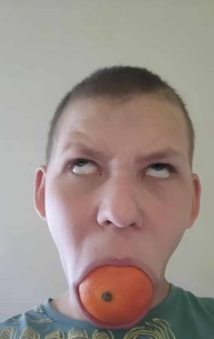 a man with an orange in his mouth