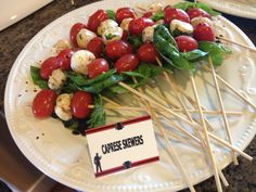 a white plate topped with tomatoes and mozzarella skewers