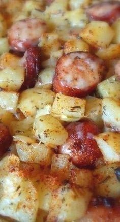 a pizza with sausage, potatoes and tomatoes is shown in close up view from the top