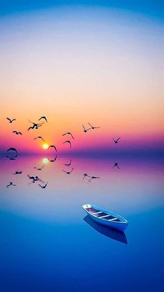 a small boat floating on top of a body of water under a colorful sky with birds flying over it