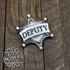 a badge with the word sheriff on it sitting on a wooden table next to a sticker