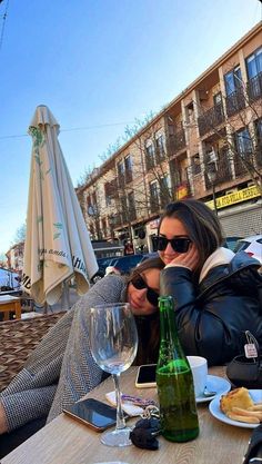 a woman sitting at a table with a bottle of wine