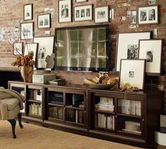 a living room filled with furniture and framed pictures on the wall behind a tv mounted to a brick wall