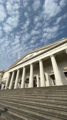 people are walking up and down the steps to an old building with columns on each side