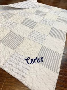 a quilted blanket with the word carrier on it, sitting on top of a wooden floor