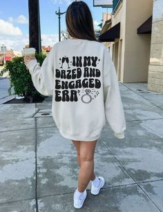 Proudly Celebrate your engaged era with style and comfort in our funny In My Dazed and Engaged Era sweatshirt. How To Order! 1-) Please, Check and Review all Photos. 2-) Select Your Product Type and Color. 3-) Select Your Product Size. 4-) Click ADD TO CART and You can go back to add more product color or You can complete the checkout process. ❤ Washing Instructions: For best results, wash inside out and lay flat to dry. Wash with like colors.  THANK YOU  Retail fit 50% Cotton 50% Polyester Tear away label Runs true to size Machine wash: warm (max 40C or 105F); Non-chlorine: bleach as needed; Tumble dry: low heat; Iron, steam or dry: medium heat; Do not dry clean Please make sure your address is correct on Etsy cause we will not be responsible for any outdated or incorrect shipping informa Fiance Gifts For Her, In My Engaged Era, Getting Engaged Outfit, Fiance Outfit, Wedding Day Shirts, Engaged Af, Bride Tee, Engagement Gifts For Her, Engagement Presents