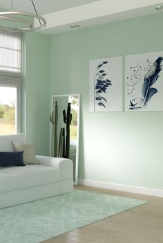 a living room with green walls and white furniture in the corner, along with two paintings on the wall