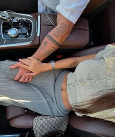 a man and woman holding hands in the back of a car