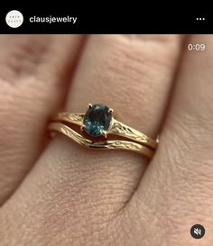 a close up of a person's hand with a gold ring and blue stone