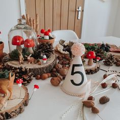 Woodland birthday set up display on a white table. Using pine cones, log cuts, moss, glass dome and toy woodland animals Woodland Birthday Decor, First Birthday Outdoor Theme, Fairy Forest Birthday Party, Forest Animals Birthday Party, Enchanted Woodland Party, Fairy Woodland Party, Toadstool Birthday Party, Mushroom Balloon Arch