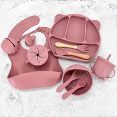 a pink baby's play set with utensils and spoons in it