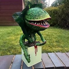 a statue of a frog with its mouth open sitting on top of a planter