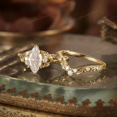 two wedding rings sitting on top of a table next to an ornate gold plated mirror