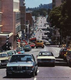 cars are driving down the street in front of tall buildings on either side of the road