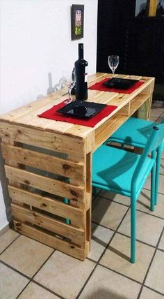 a table made out of pallet wood with two blue chairs and a wine glass on top