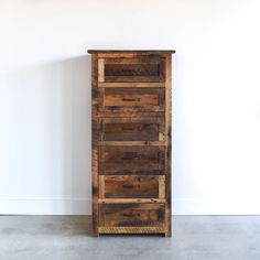 a tall wooden cabinet sitting on top of a cement floor next to a white wall