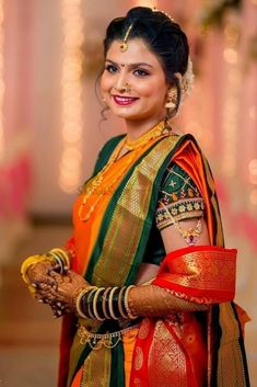 a woman in an orange and green sari with her arms crossed, smiling at the camera