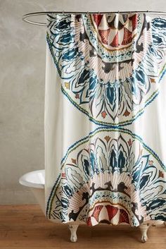 a shower curtain with an abstract design on it and a white bath tub in the background