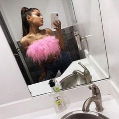 a woman is taking a selfie in the mirror with her cell phone and wearing a pink feather boa