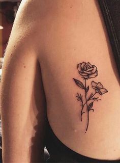 a woman's back with a rose tattoo on it