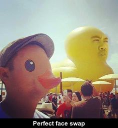 a man standing next to a giant rubber duck in the middle of a crowd at an outdoor event