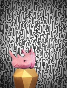 a pink bird sitting on top of a golden vase in front of a black and white wall