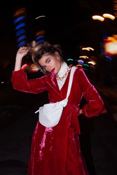 a woman in a red velvet dress is posing for the camera with her hand on her head