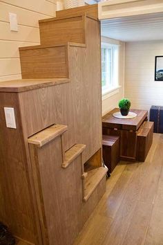 there is a small wooden staircase leading to the second floor in this tiny home with wood floors and white walls