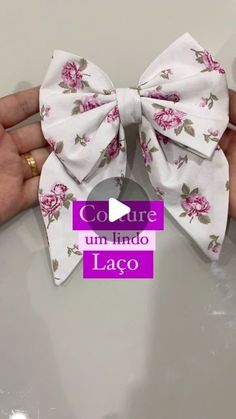 a person holding a white bow with pink flowers on it and the words coutre um lindo lago