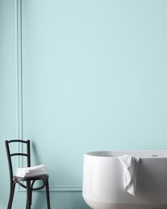 a chair sitting next to a bathtub in a room with blue walls and flooring