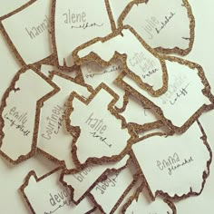 some white and gold glittered paper tags with words on them that spell out the names of cities