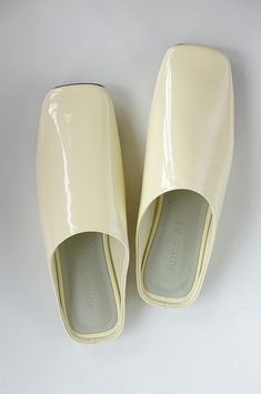 Spring yellow patent leather slippers made of real leather. Get them for a chic and comfy look! Modern Patent Leather Slip-on Sandals, Summer Patent Leather Mules With Round Toe, Chic Cream Flat Mules, Summer Patent Leather Slip-on Mules, Spring Patent Leather Slip-on Mules, Summer Patent Leather Closed Toe Mules, Elegant White Summer Clogs, Cream Slip-on Clogs For Summer, Classic Patent Leather Sandals For Spring