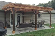 a covered patio with chairs and tables in front of a house on a sunny day