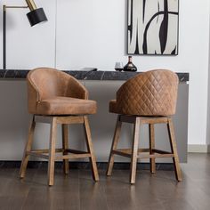 two brown chairs sitting next to each other on top of a hard wood floored floor