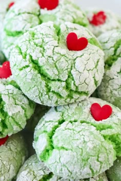 some green and red cookies with hearts on them are stacked up in a white bowl