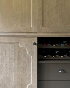 a cabinet with wine bottles in it and two drawers on the bottom right hand side