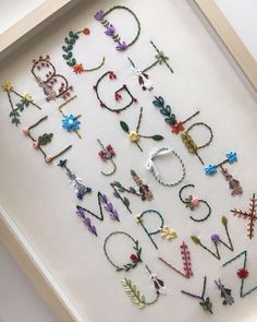 the letters are made up of different types of beads and flowers on a white surface