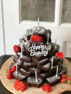 a birthday cake made to look like it is stacked on top of each other with candles and strawberries