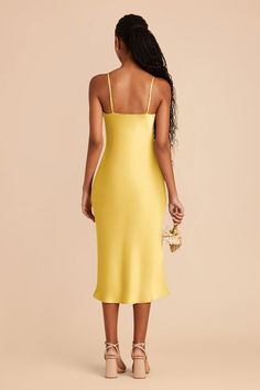 a woman in a yellow dress is looking back at the camera and she has her hand on