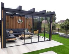 an outdoor living area with glass walls and furniture