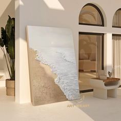 a large painting on the wall in front of a living room with an ocean view