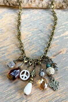 a necklace with charms on it sitting on top of a wooden table next to a rock