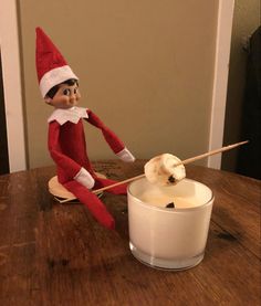 an elf is sitting on the table with a stick in front of a glass of milk