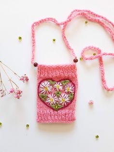 a crocheted pink purse with flowers in the shape of a heart on it